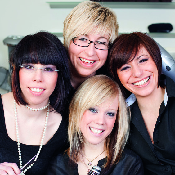 Vier Friseurinnen lächeln in die Kamera